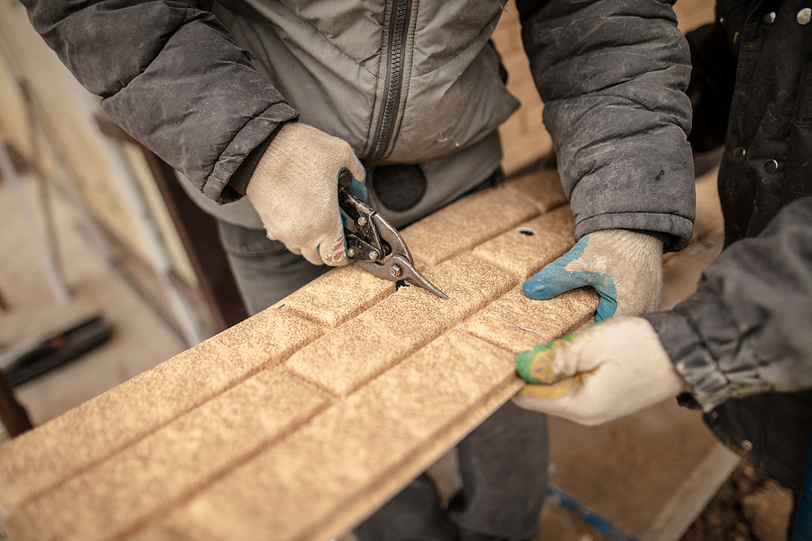 Installing Siding On The Wall Of The House Under The Brick .